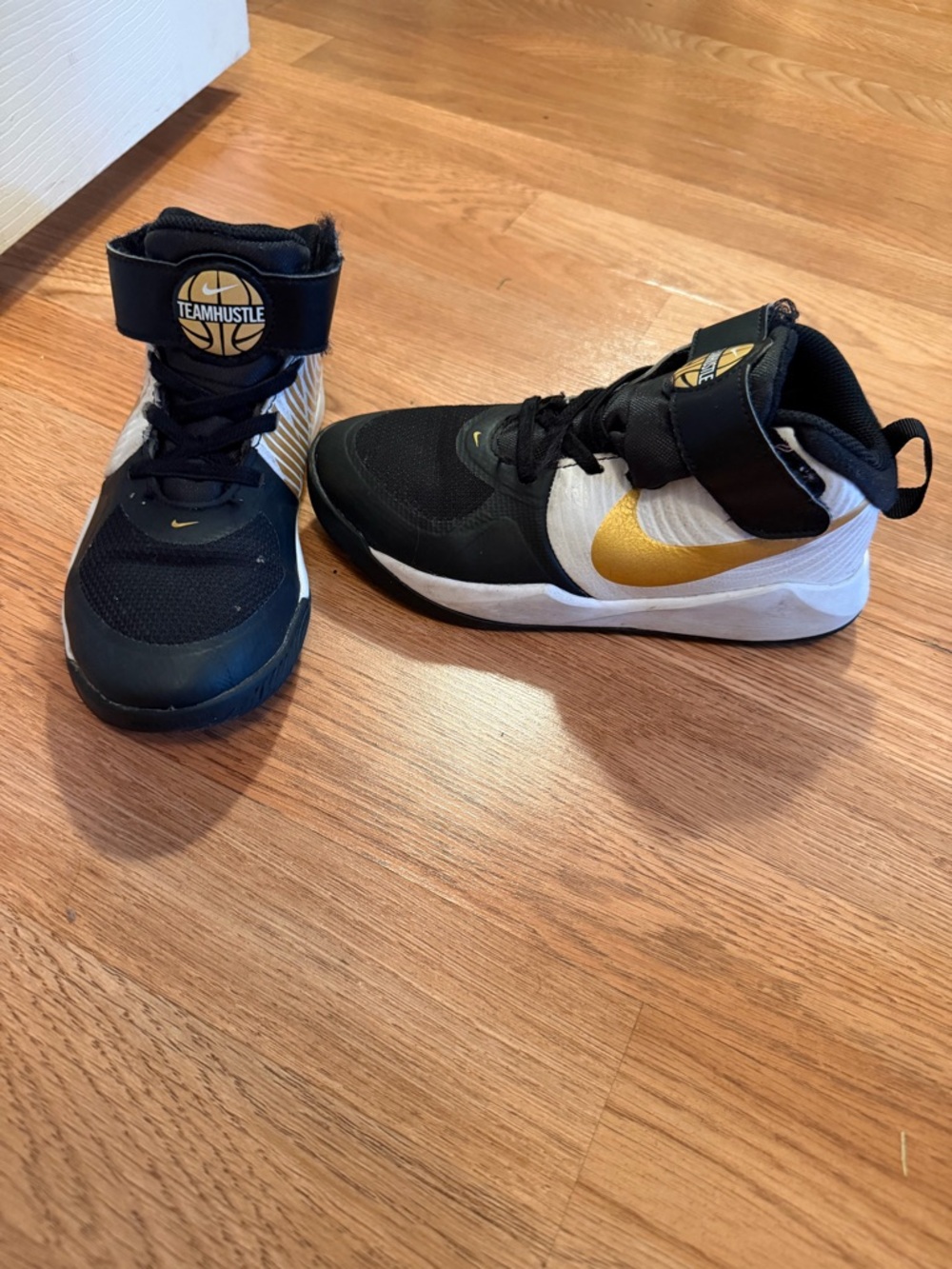 Nike Team Hustle Kids' Black and White Sneakers with Gold Swoosh